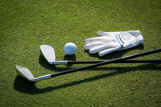Golf clubs, a golf ball, and a white golf glove resting on a well-maintained putting green, ready for a round of golf.