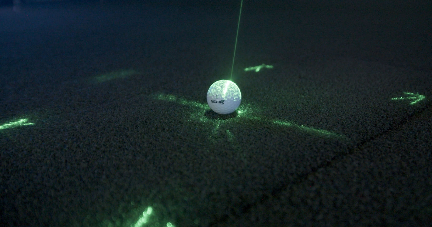 A golf ball reflecting the green lights of the APOGEE indoor golf simulator Laser Launch Pad