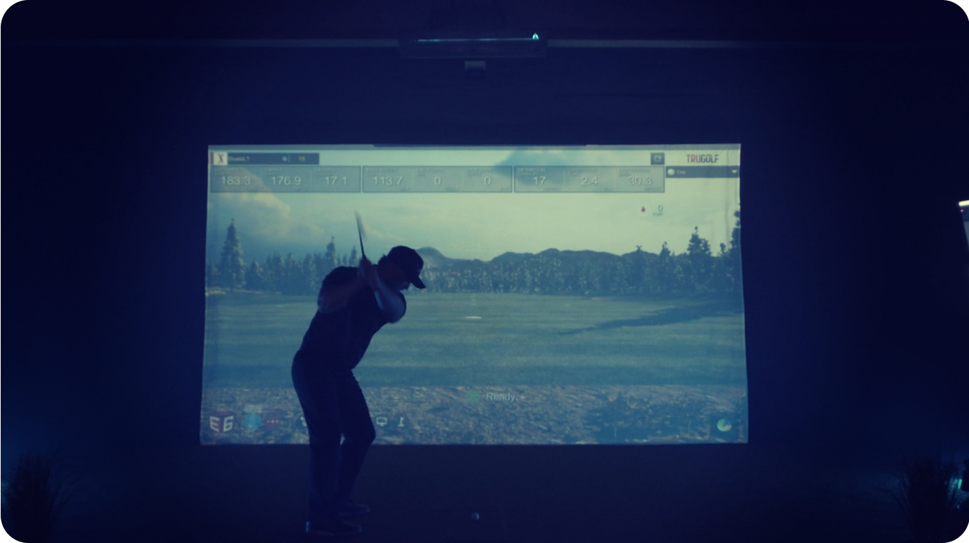 A man standing in front of the APOGEE indoor golf simulator