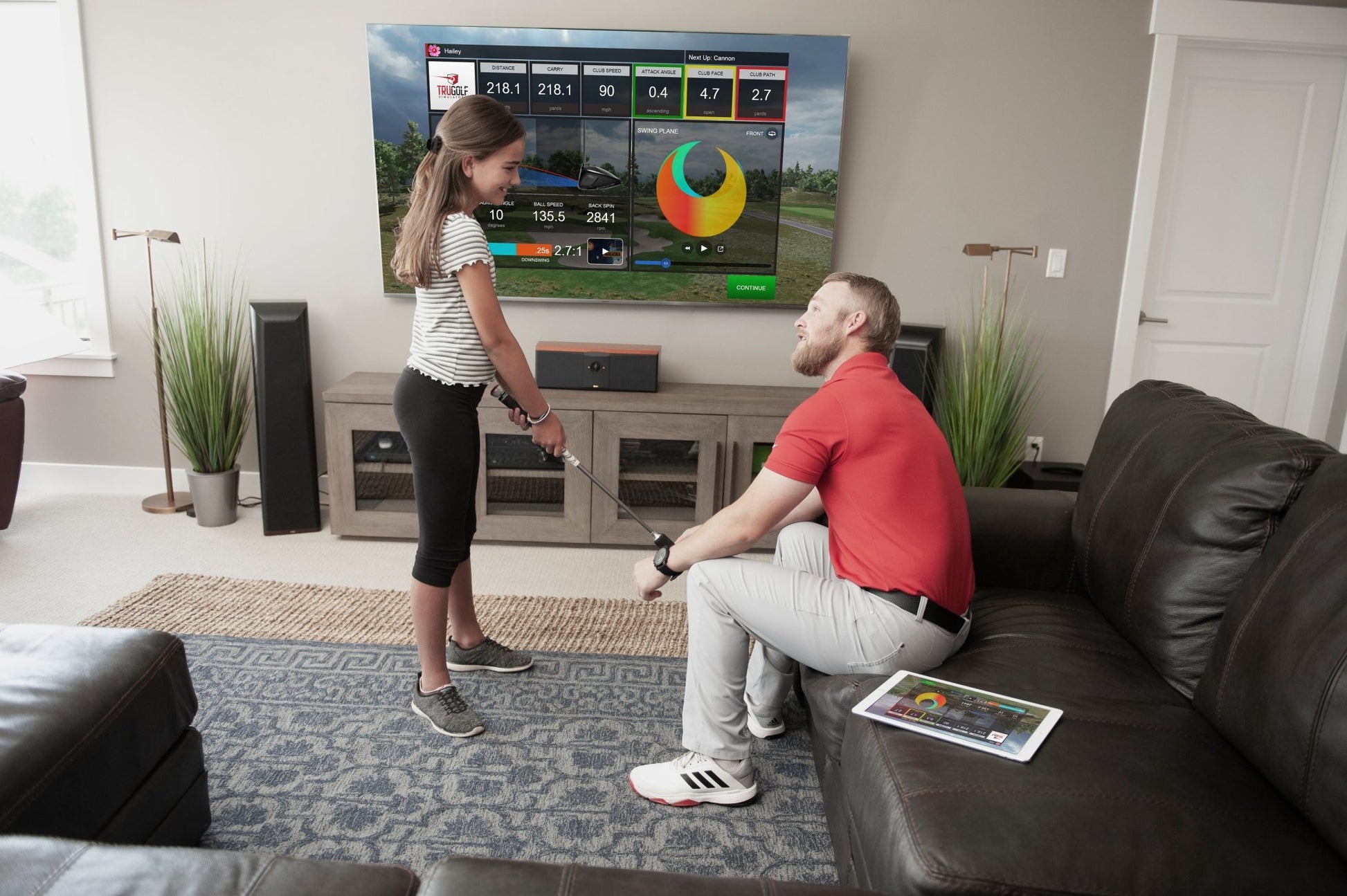 Man and girl using the TruGolf mini simulator at home